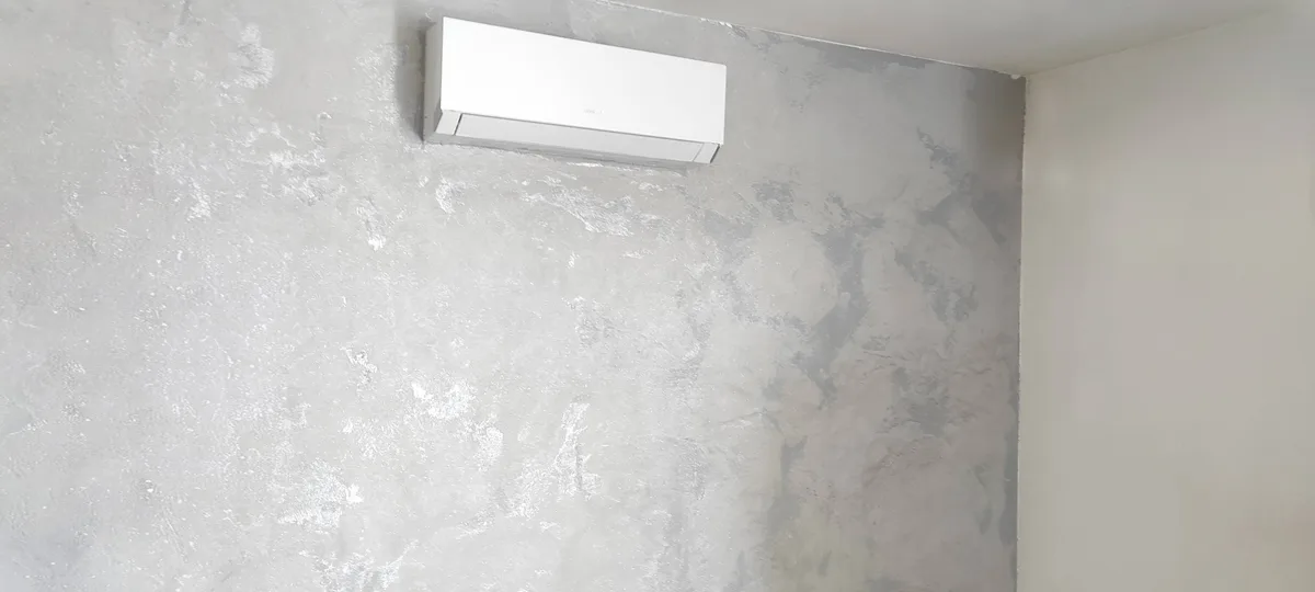 Hotová klimatizační jednotka na stěně s dekorativní stěrkou v moderním interiéru